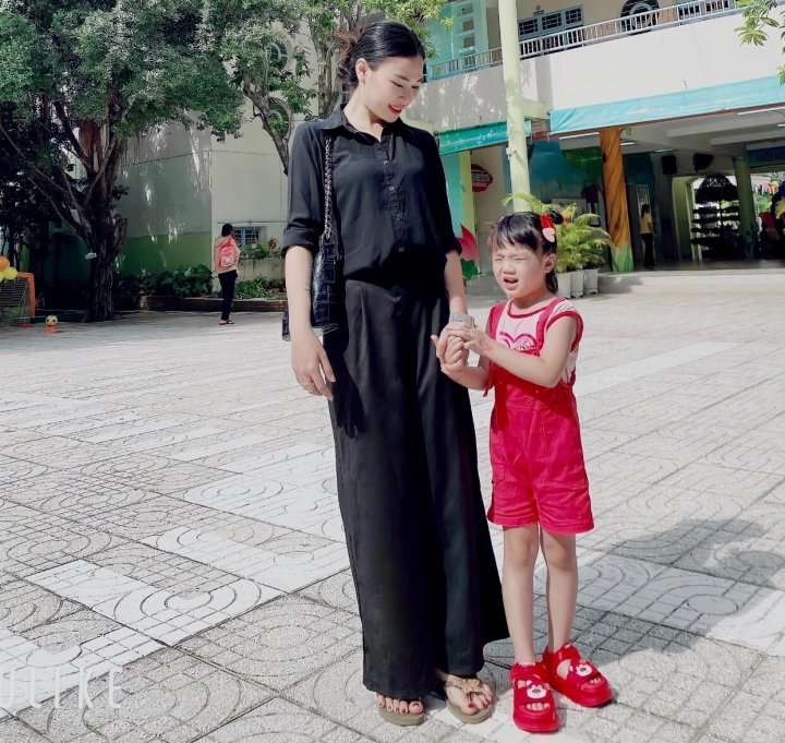 Bạn nhỏ nào cũng đều bỡ ngỡ, chỉ muốn ở mãi trong vòng tay chở che của mẹ. Ngày tựu trường, em bịn rịn nắm chặt lấy mẹ. (Ảnh: Tạ Nhi)